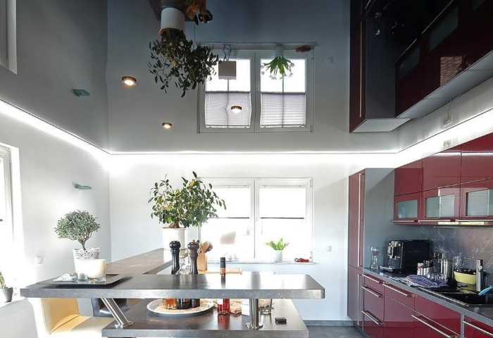 Renovierte Küche mit roten Küchenmöbeln und schwarzer Glanzspanndecke als moderne Deckengestaltung