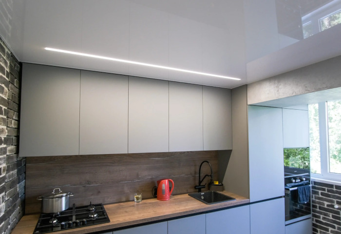 Modern renovierte weiße Küche mit weißer Glanzspanndecke und integrierter LED-Lichtlinie